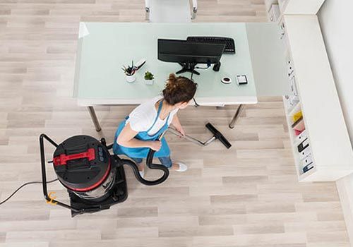 mujer limpiando piso de oficina